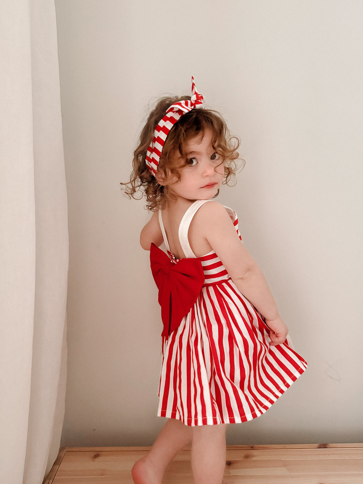 Red and white striped cotton dress, square neck, sleeveless with wide straps, red bow at back, A-line skirt, knee length, for Christmas and party.