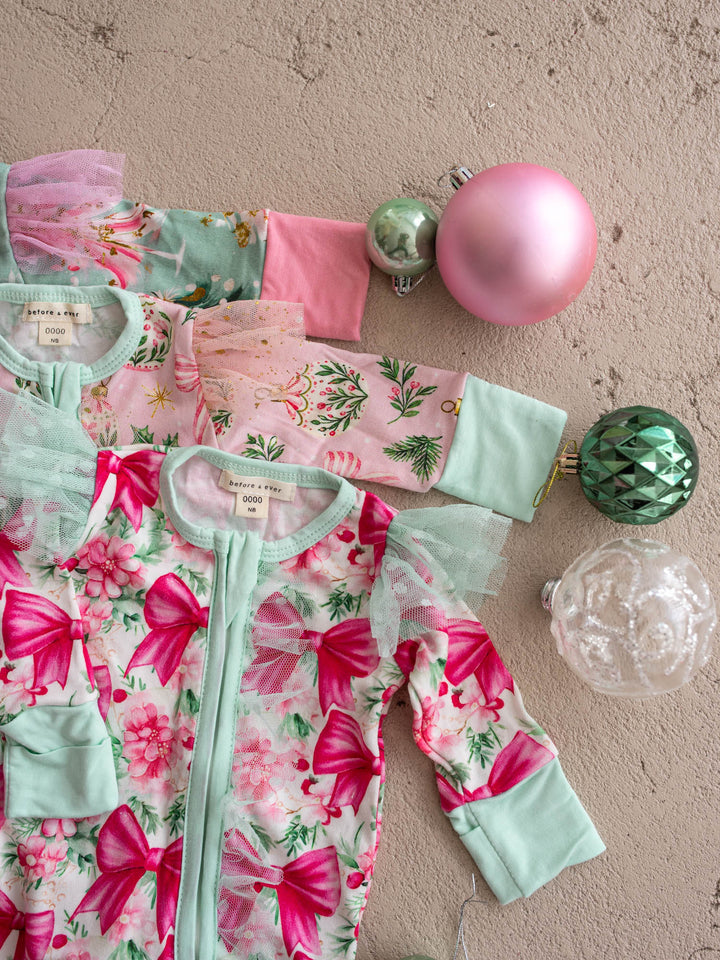 All I Wish Christmas baby onesies and topknots laid out together including the Pink Bow print - Before & Ever Kids