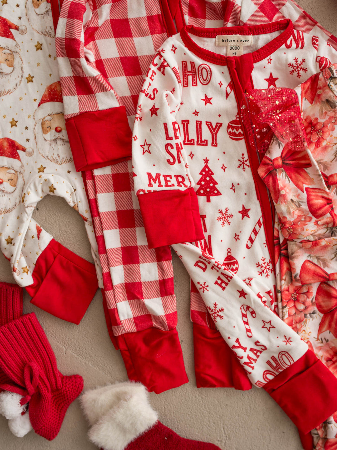 All I Wish Christmas baby onesies laid out together including the Red Gingham print - Before & Ever Kids