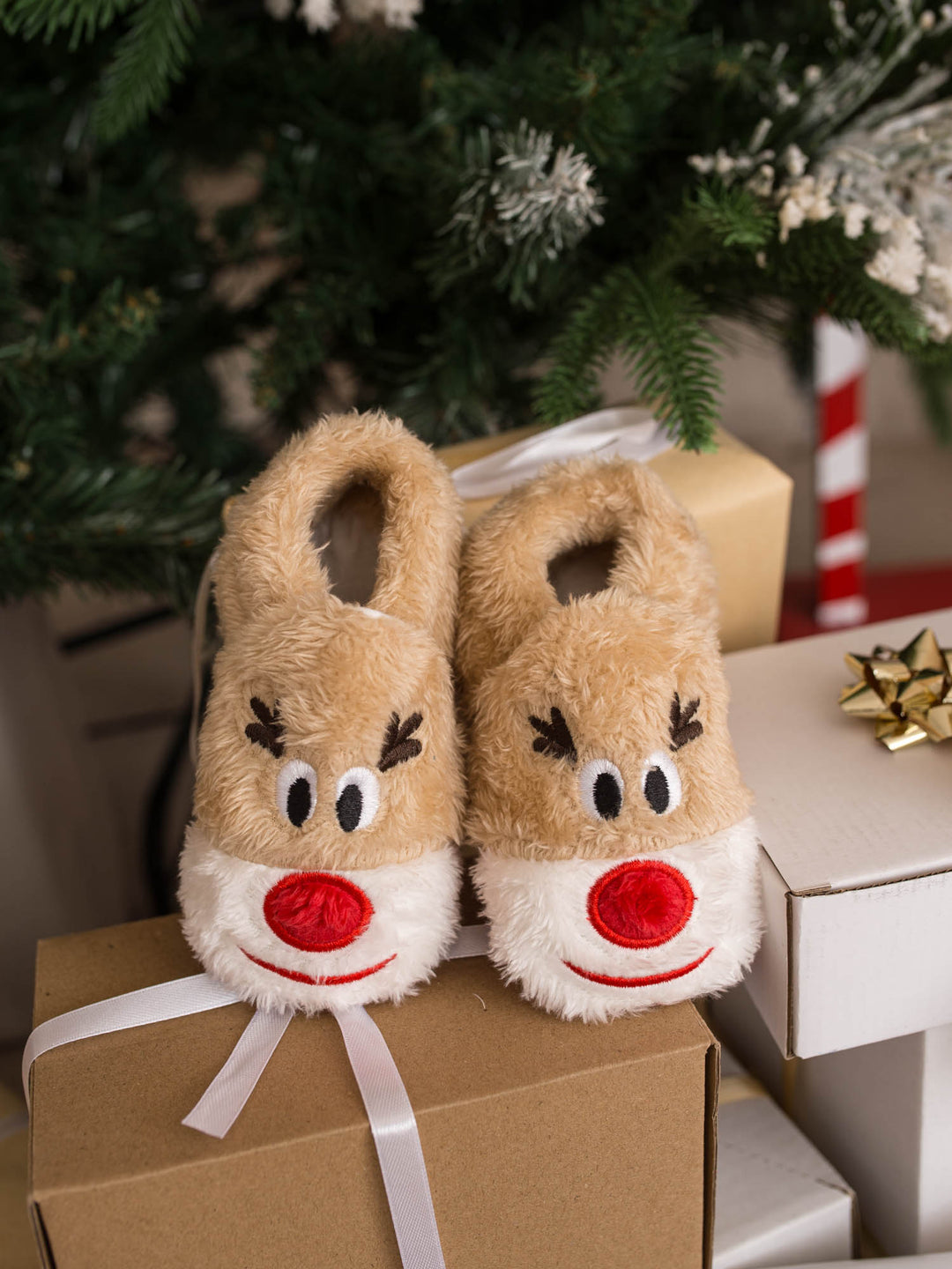 Baby Rudolph Slippers tan reindeer slippers on a gift box by the tree - Before & Ever Kids
