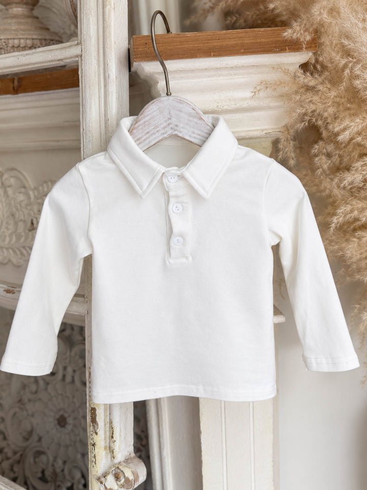 Everyday Cotton Polo, white long sleeve cotton polo, hanging on a white wooden hanger, full front - Before & Ever Kids