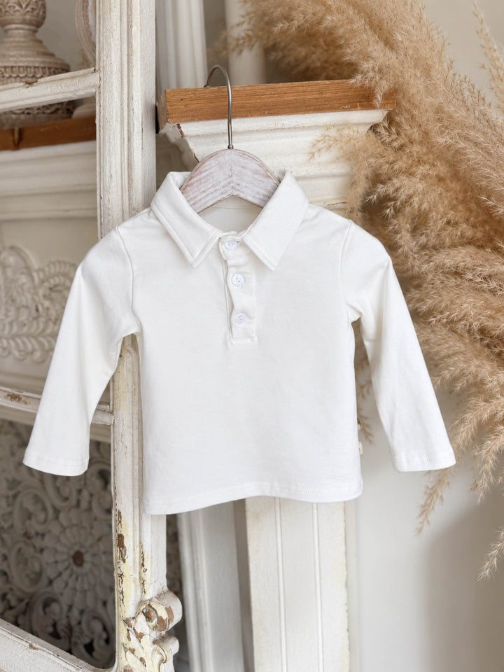 Everyday Cotton Polo, white long sleeve cotton polo, hanging on a hanger beside dried pampas - Before & Ever Kids