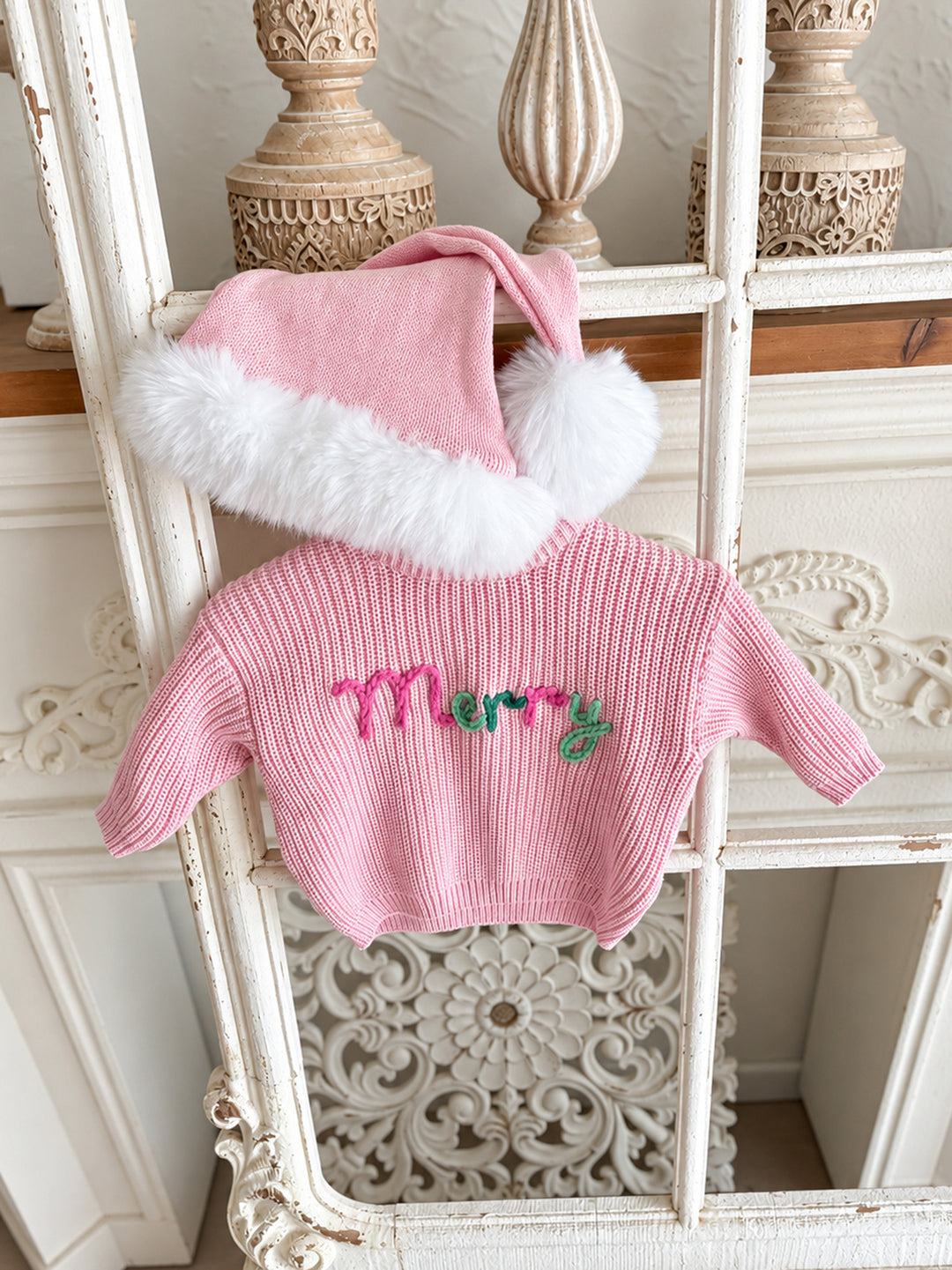 Baby pink knitted Santa hat with white fluffy trim and pom-pom, styled above a pink Merry knit sweater