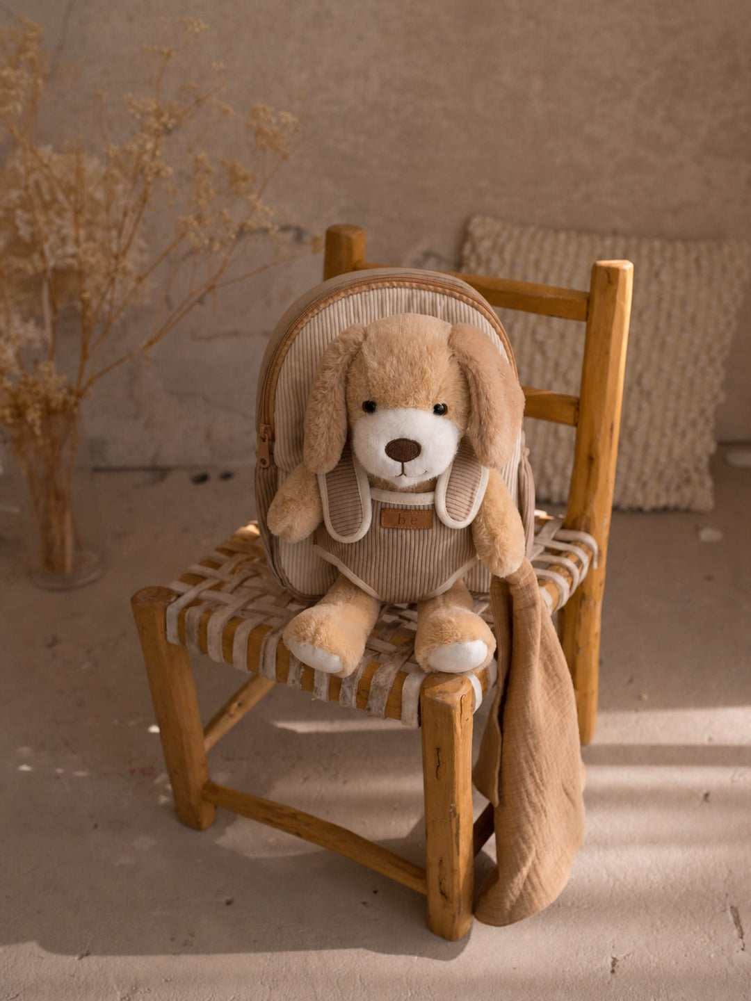 Milo the Puppy plush backpack for kids, puppy sitting in the backpack on a chair - Before & Ever Kids