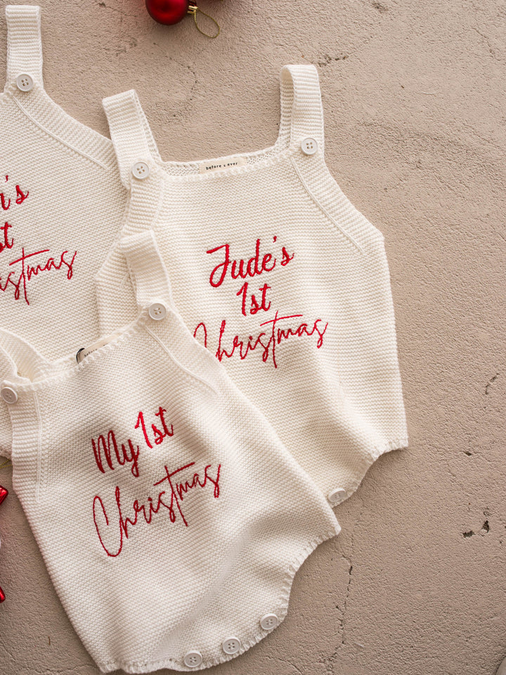 My 1st Christmas Singlet Romper in milk cotton knit with red embroidery, beside a personalised name romper and candy decorations - Before & Ever Kids