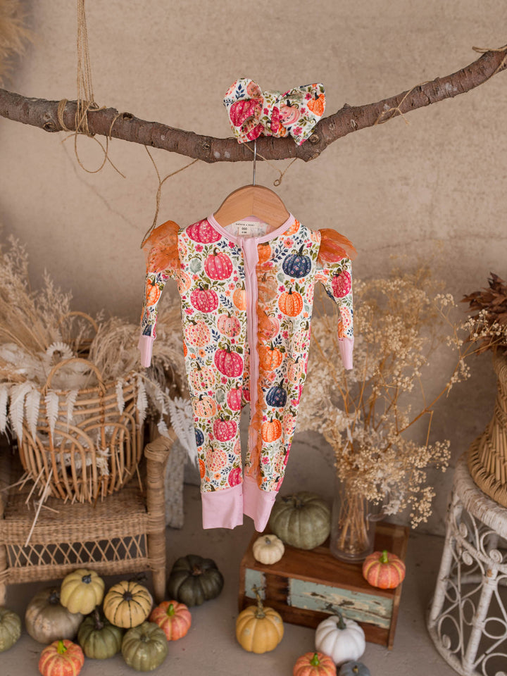 Patch Perfect pumpkin onesie hanging with its matching floral topknot headwrap - Before & Ever Kids
