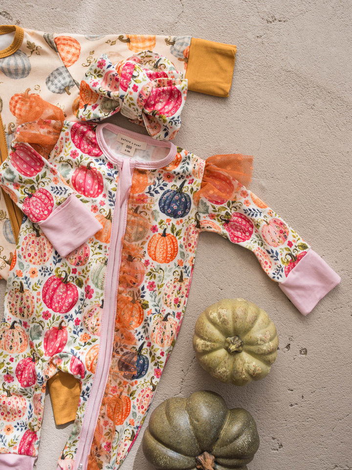 Patch Perfect pumpkin floral onesie flat lay with topknot beside Patch Ready onesie - Before & Ever Kids