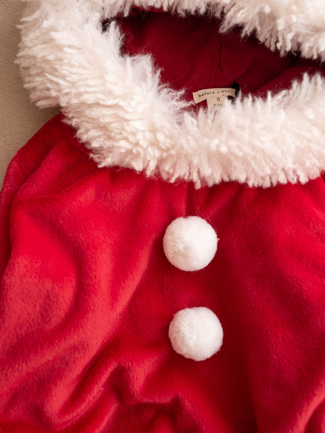 Close up of the white fluffy collar and pom-poms on the Santa Baby Romper - Before & Ever Kids