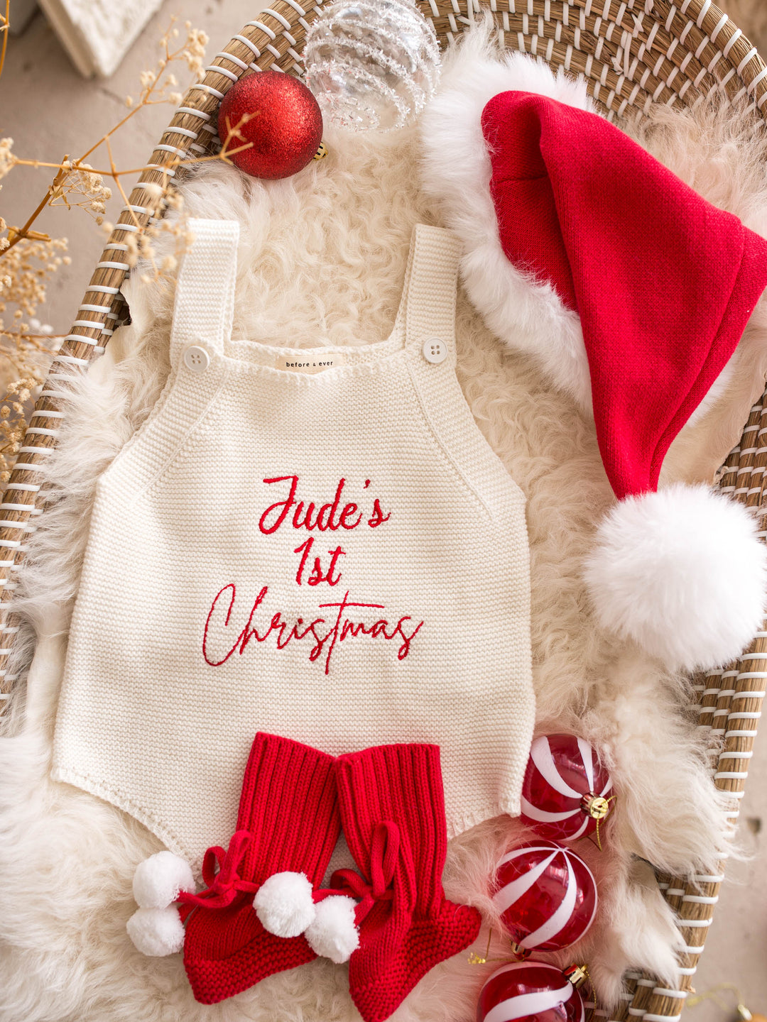 Say My Name Christmas Singlet Romper in milk cotton knit with a personalised name in red, with a red Santa hat and red knitted booties - Before & Ever Kids