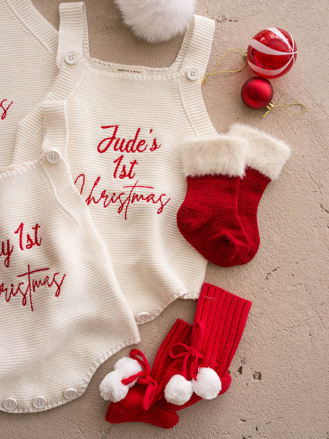 Say My Name Christmas Singlet Romper in milk cotton knit with a personalised name in red, flat with red knitted booties - Before & Ever Kids