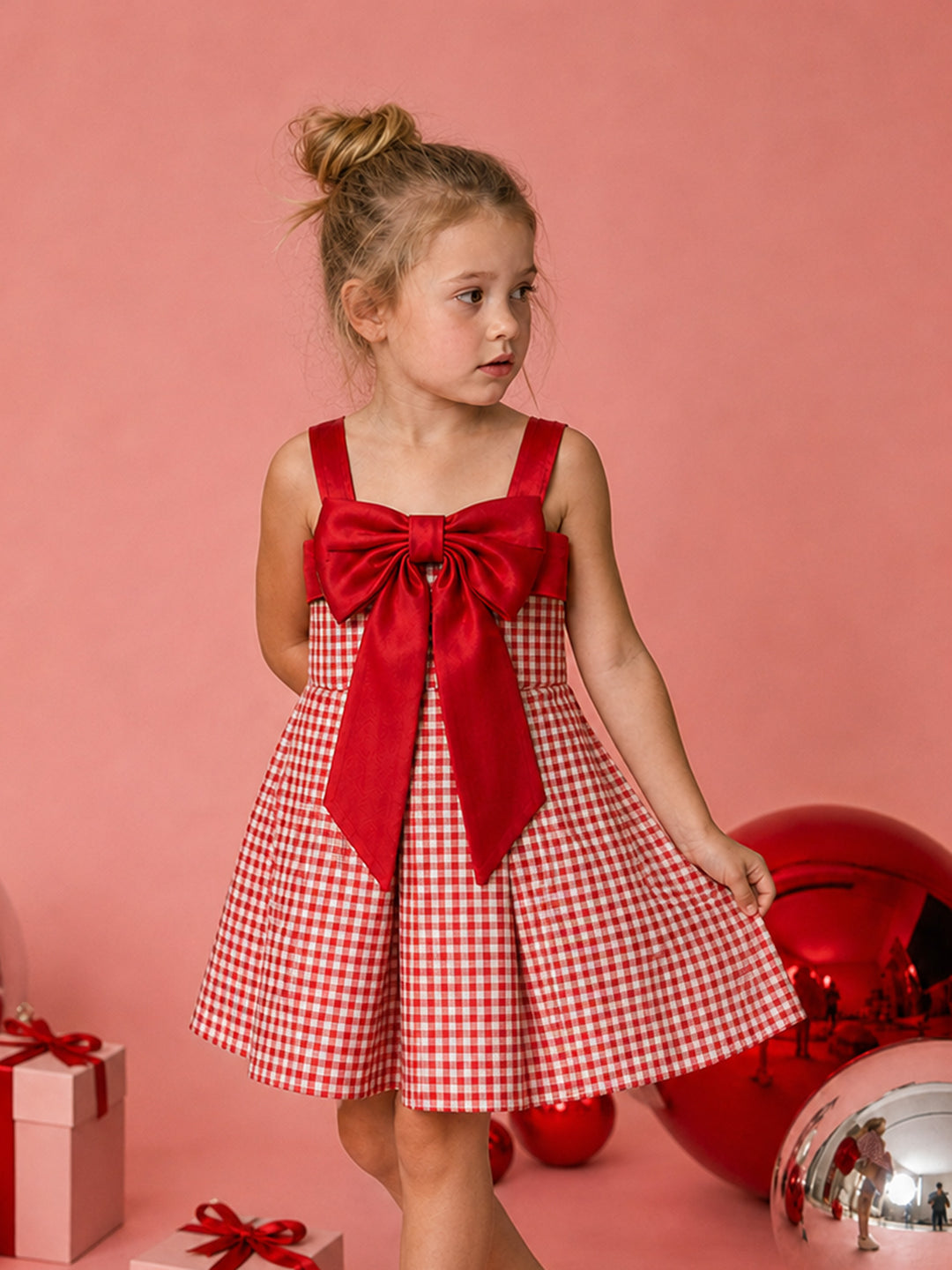 Sweet as Pie red and white gingham Christmas dress with a red satin bow, holding out the pleated skirt beside red baubles