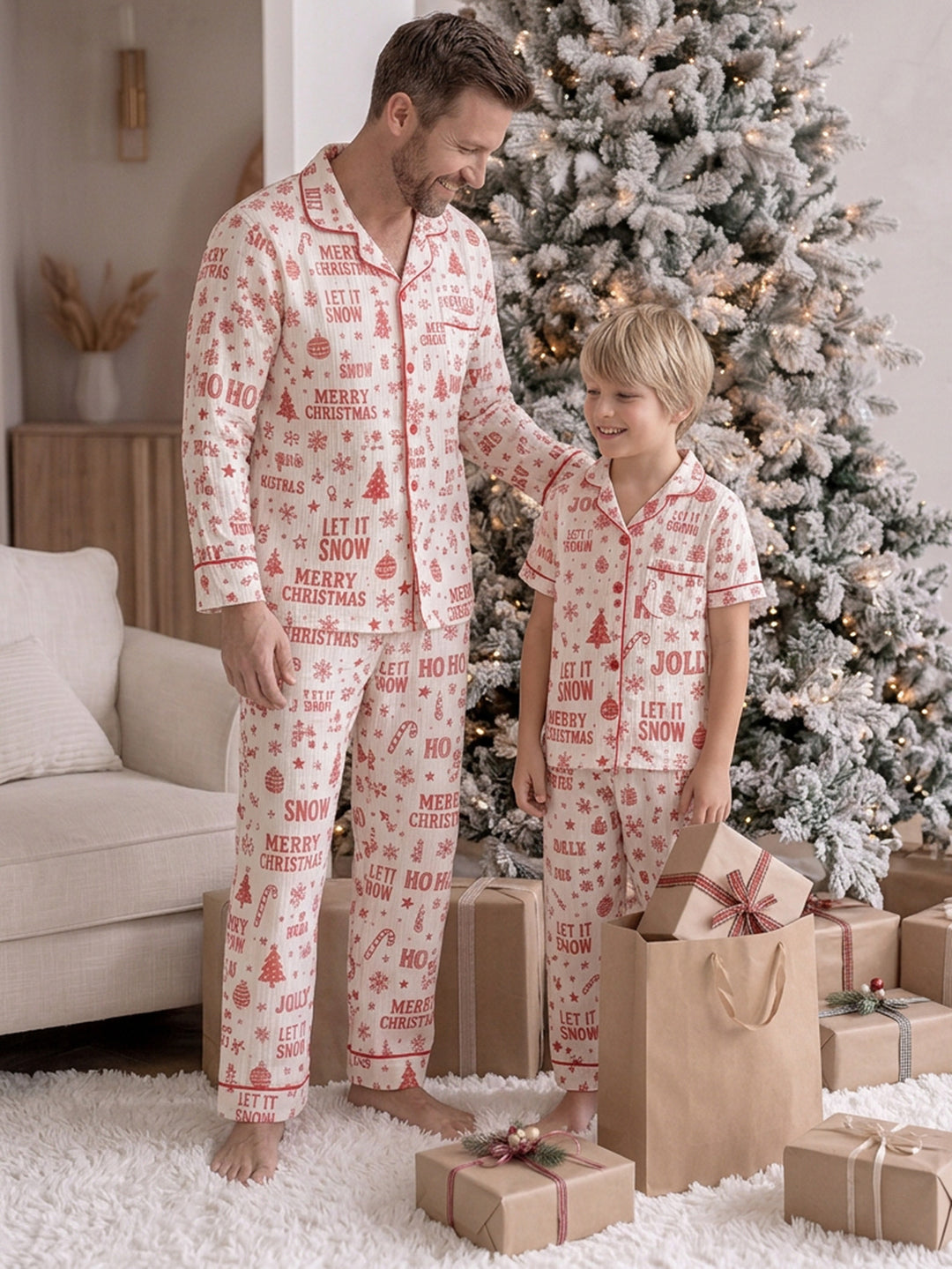 Twas the Night family Christmas pyjamas, white cotton muslin with a red Christmas print, dad standing full length in the long sleeve shirt and long pants beside the boy by the tree - Before & Ever Kids