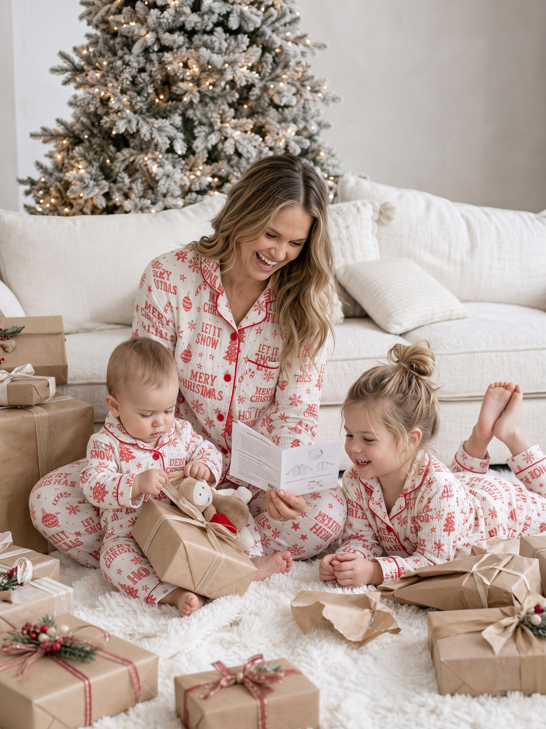 Twas the Night family Christmas pyjamas, white cotton muslin with a red Christmas print, mum, girl and baby on the rug with presents - Before & Ever Kids
