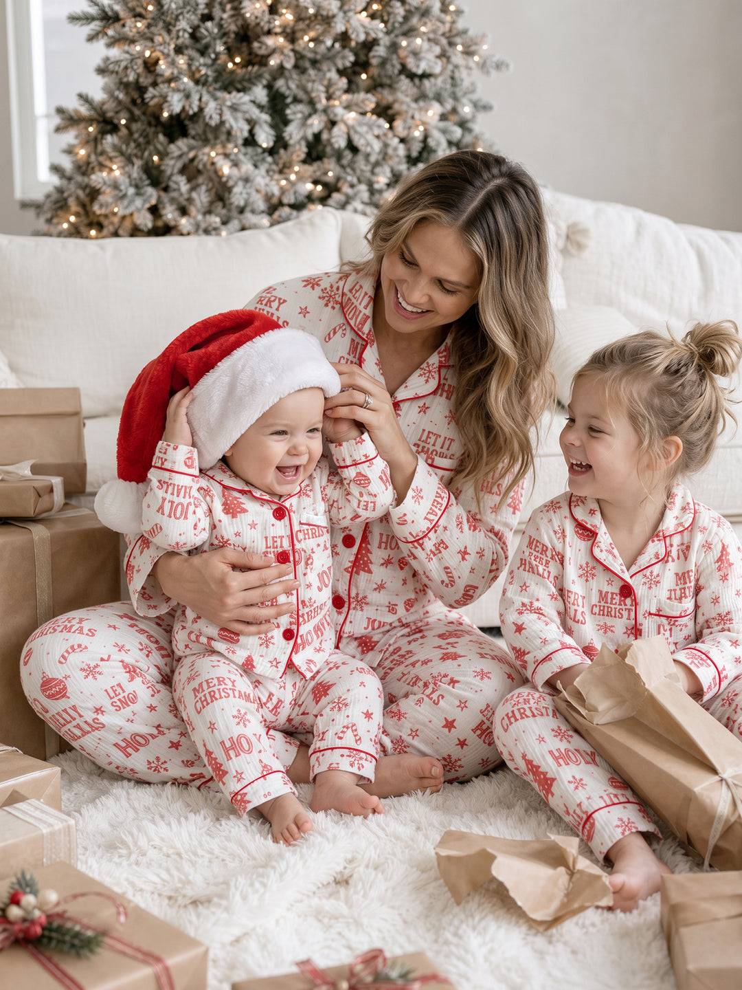 Twas the Night family Christmas pyjamas, white cotton muslin with a red Christmas print, mum in the long sleeve shirt and long pants with the baby in a Santa hat and the girl in long sleeves - Before & Ever Kids