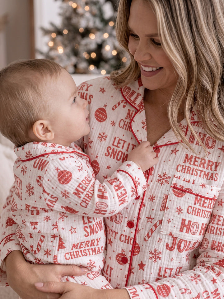 Twas the Night family Christmas pyjamas, white cotton muslin with a red Christmas print, mum in the long sleeve shirt holding the baby, close - Before & Ever Kids