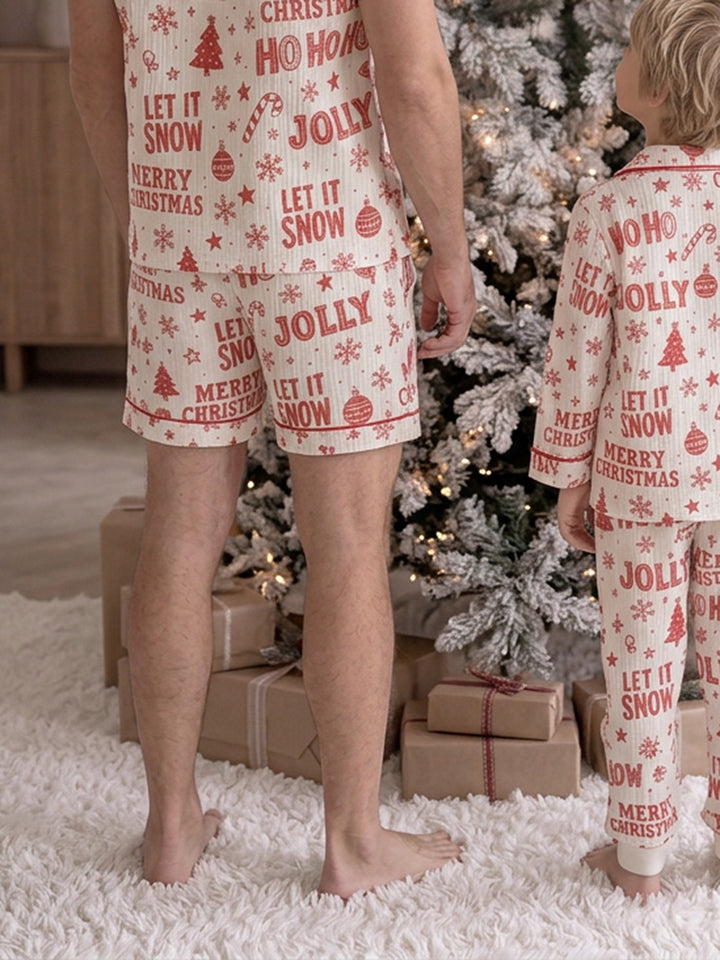 Twas the Night family Christmas pyjamas, white cotton muslin with a red Christmas print, close crop of dad's and the boy's shorts standing by the tree, back view - Before & Ever Kids